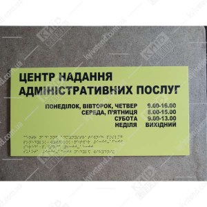 Фото на дверях - тактильна табличка жовтого кольору з написом центр надання послуг для людей з інвалідністю та шрифтом Брайля